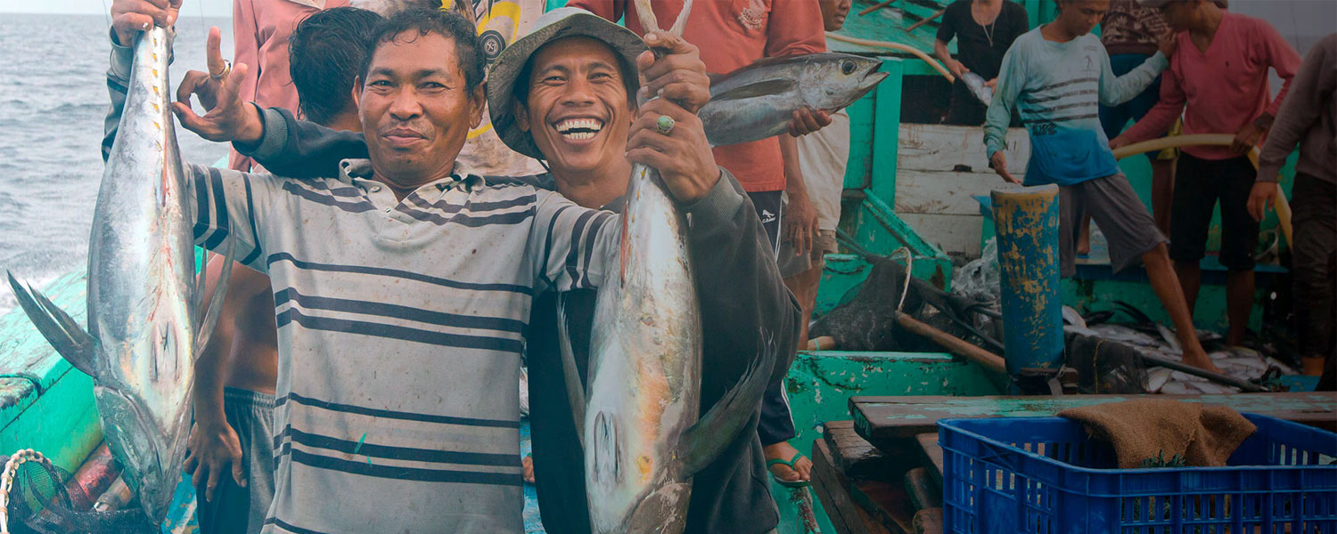 Men holding up catches of fish smiling at the camera