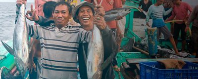Men holding up catches of fish smiling at the camera