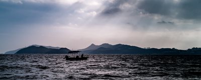Silhoutte of fisherman in small boat with islands in the background