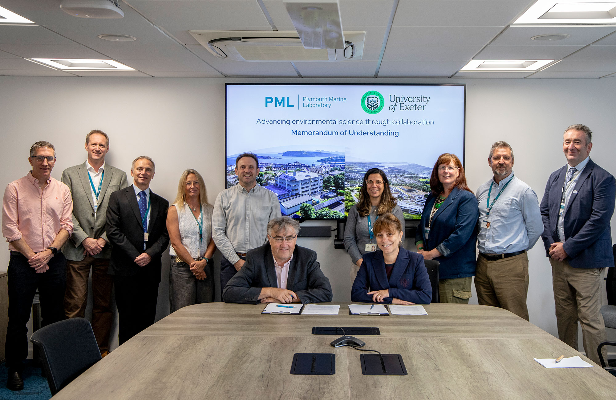 Group shot of the signing with banner in the background that says "advancing environmental science through collaboration" with the two organisations' logos